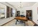 Stylish home office with dark wood furniture, a unique chandelier, and plenty of natural light at 1113 Cryptic Wood Ave, Fuquay Varina, NC 27526