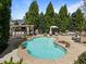 Inviting backyard pool area featuring a covered bar, lounge chairs, and lush landscaping for outdoor entertaining at 116 Arlen Park Pl, Holly Springs, NC 27540