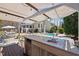 Covered outdoor kitchen with stainless steel appliances and a stone countertop overlooking the pool at 116 Arlen Park Pl, Holly Springs, NC 27540