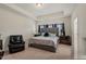 Well-lit bedroom with a large bed, tray ceiling, and stylish black leather recliner at 2216 Tanners Mill Dr, Durham, NC 27703