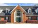 Beautiful brick building entrance featuring a grand arched window, green doors, dormer windows, and manicured bushes at 2245 Ventana Ln, Raleigh, NC 27604
