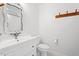 Bathroom with white cabinets and sink, a white toilet, and a decorative mirror at 2330 Glascock St, Raleigh, NC 27610