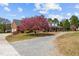Brick home with inviting porch and a colorful flowering tree, complemented by a gravel driveway at 3030 Old Stage S Rd, Erwin, NC 28339