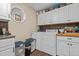 A laundry room with a washer, dryer, white cabinets, brown backsplash and wood look flooring at 3030 Old Stage S Rd, Erwin, NC 28339