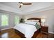 A comfortable bedroom featuring tray ceilings, hardwood floors, and bright natural light at 306 Lochside Dr, Cary, NC 27518