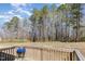 Backyard with a wooden deck including a grill, overlooking a large grassy lawn and natural tree line beyond at 31 E Dentaires Way, Willow Springs, NC 27592