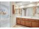 Bright bathroom with double sinks, wood cabinets, large mirror, and a tub next to the window at 3308 Forest Mill Cir, Raleigh, NC 27616