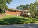Beautiful backyard with an open lawn, a brick house with white trim and built in swing set at 3680 15-501 N, Pittsboro, NC 27312