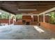 Spacious carport with brick fireplace, wood storage, exposed rafters, and concrete flooring at 3680 15-501 N, Pittsboro, NC 27312