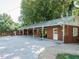 View of brick building with carport, concrete driveway, basketball hoop, and lush landscaping at 3680 15-501 N, Pittsboro, NC 27312