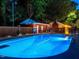 Dusk view of an in-ground pool with diving board, seating, and pool house, perfect for relaxing at 3680 15-501 N, Pittsboro, NC 27312
