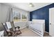 This Bedroom features a white crib, rocking chair, natural light, and a blue accent wall at 5705 Dean Ave, Raleigh, NC 27616