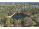 Scenic aerial view of a tranquil pond surrounded by lush greenery and mature trees, offering a peaceful retreat at 5705 Dean Ave, Raleigh, NC 27616