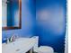 Bright blue bathroom featuring a white sink and toilet with dark wood-trimmed mirror at 761 S Eighth St, Mebane, NC 27302