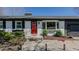 Close-up of the white brick home featuring a vibrant red front door and well-manicured landscaping at 761 S Eighth St, Mebane, NC 27302