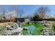 A green backyard pond is surrounded by rock, statuary, a small building, and mature trees at 761 S Eighth St, Mebane, NC 27302