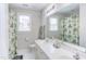 Bright bathroom with a double vanity, tiled floors and shower with decorative floral curtain at 7816 Tylerton Dr, Raleigh, NC 27613
