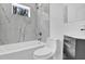 Updated bathroom showcasing the new fixtures including tiled tub, toilet, vanity, and window at 810 Cox Ave, Durham, NC 27701