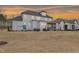 View of a large backyard with a hot tub, patio, screened-in porch, and play set against a sunset sky at 83 Inspiration Way, Fuquay Varina, NC 27526