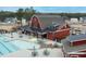 Aerial view of community pool area with lounge seating, umbrellas, and a recreation barn with nearby neighborhood at 83 Inspiration Way, Fuquay Varina, NC 27526