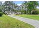 Well-maintained single story home featuring a long driveway, green lawn, and mature trees at 911 Williams Rd, Raleigh, NC 27610