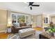 Open living room with large windows, ceiling fan, fireplace view and hardwood floors at 105 Blanchard St, Fuquay Varina, NC 27526