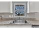 A close-up of the stainless steel kitchen sink with white cabinets and gray and white countertops at 1107 Pale Moss Dr, Durham, NC 27704
