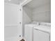 Bright laundry room with white washer, dryer, door, and shelving at 1107 Pale Moss Dr, Durham, NC 27704