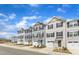 Street view of townhomes with colorful exteriors, garages, and landscaped front yards under a blue sky at 1107 Pale Moss Dr, Durham, NC 27704