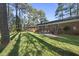 Backyard view of a home's brick exterior, outdoor patio, and tall pine trees creating shade at 11801 Strickland Rd, Raleigh, NC 27613