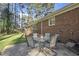 Backyard patio with brick exterior and a table and chairs sits under tall pine trees with lush green grass at 11801 Strickland Rd, Raleigh, NC 27613