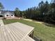 Expansive backyard featuring a wood deck, lush lawn, and a view of the surrounding trees and modern home at 170 Cherry Bark Dr, Youngsville, NC 27596