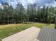 A backyard features a wooden deck, expansive green lawn, and a tree-lined border for privacy at 170 Cherry Bark Dr, Youngsville, NC 27596