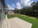 View of lush green backyard, a modern house, and a wooden deck on a sunny day at 170 Cherry Bark Dr, Youngsville, NC 27596