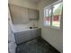 Laundry room with gray cabinets, white countertops, stylish hexagonal flooring and a bright window at 170 Cherry Bark Dr, Youngsville, NC 27596