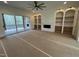 Bright living room featuring a fireplace, custom built-ins, fan, and sliding doors to the porch at 170 Cherry Bark Dr, Youngsville, NC 27596