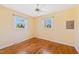 Empty bedroom showcasing hardwood floors, two windows, a ceiling fan, and neutral paint at 1805 Lawrence Rd, Hillsborough, NC 27278