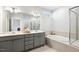Bright bathroom features double vanity with gray cabinets, separate shower, and soaking tub at 190 Salem Village Dr, Fuquay Varina, NC 27526