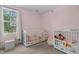 Charming pink Bedroom with two cribs, soft seating, and plenty of natural light at 20 W Park Ln, Sanford, NC 27332