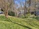 Spacious yard with verdant lawn, mature trees, and glimpses of a white house with a porch at 2005 Bridgeport Dr, Raleigh, NC 27615