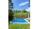 Backyard pool features a stone waterfall, patio, and multiple lounge chairs surrounded by lush greenery and a blue sky at 2613 Forest Lake Ct, Wake Forest, NC 27587