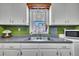 The kitchen features white cabinets, green backsplash, a stainless steel sink, and a window with wine glass storage at 300 Lakeside Dr, Garner, NC 27529