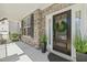 Charming front porch with a wreath on the door, stone accents, and lush potted plants at 3409 Lily Orchard Way, Apex, NC 27539