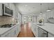 Bright, open kitchen with white cabinets, marble countertops, stainless steel appliances, and hardwood floors at 3409 Lily Orchard Way, Apex, NC 27539