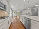 Bright kitchen has a marble island, stainless steel appliances, white cabinets, and hardwood floors at 3409 Lily Orchard Way, Apex, NC 27539