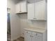 Functional laundry room with overhead storage, white cabinets, quartz countertops, and stylish herringbone backsplash at 4013 Kingcraig Ln, Zebulon, NC 27597