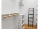 Walk-in closet with white shelving, wooden rods, and a dark metal shelving unit at 402 Chavis Way, Raleigh, NC 27601