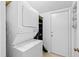 A laundry area features a stacked washer and dryer set next to a side entry door and wire storage at 4633 Edwards Mill Rd, Raleigh, NC 27612