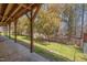 View of a covered patio overlooking a spacious backyard with a chain-link fence and mature trees at 501 Hiddenbrook Dr, Durham, NC 27703