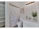 Well-lit half bath with modern fixtures, and storage shelving, along with floral shower curtain at 501 Hiddenbrook Dr, Durham, NC 27703